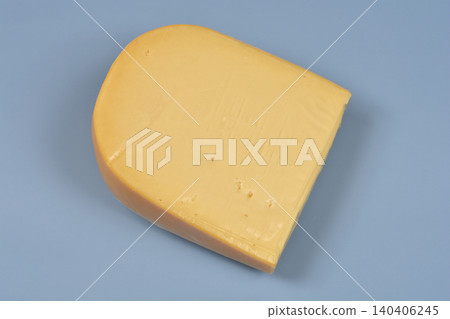 A block of semi hard yellow Gouda cheese on a blue background A block of semi hard yellow Gouda cheese on a blue background 140406245