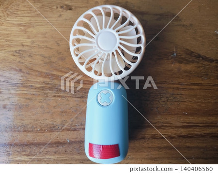 Compact Mini Electric Fan for Personal Cooling on a wooden table Compact Mini Electric Fan for Personal Cooling on a wooden table 140406560