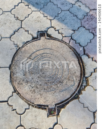 Concrete manhole cover on patterned pavement in urban setting with weathered texture Concrete manhole cover on patterned pavement in urban setting with weathered texture 140406618