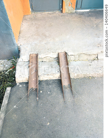Rusty metal ramps on urban sidewalk with concrete steps and cracked pavement Rusty metal ramps on urban sidewalk with concrete steps and cracked pavement 140406649