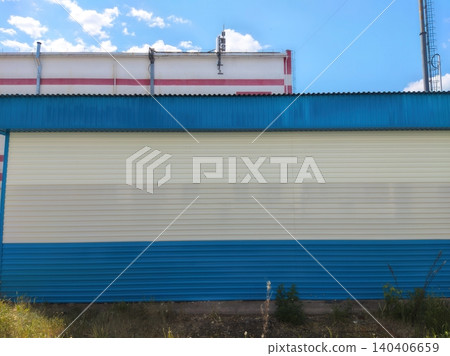Industrial building with blue and white metal siding under clear sky Industrial building with blue and white metal siding under clear sky 140406659