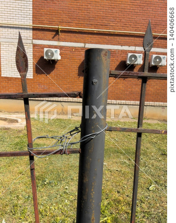 Weathered iron fence with barbed wire against brick wall background Weathered iron fence with barbed wire against brick wall background 140406668