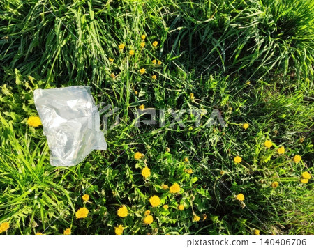 Plastic bag littering lush green grass among yellow dandelions in a natural setting Plastic bag littering lush green grass among yellow dandelions in a natural setting 140406706