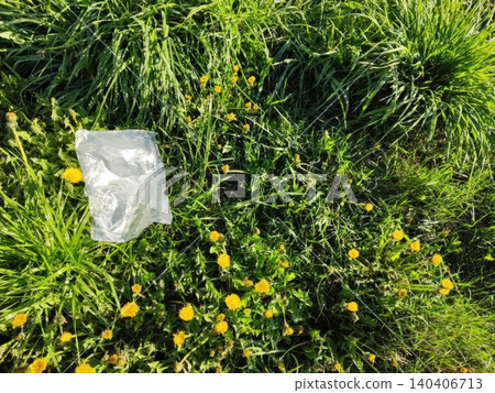 Plastic litter among vibrant dandelions in lush green grass Plastic litter among vibrant dandelions in lush green grass 140406713