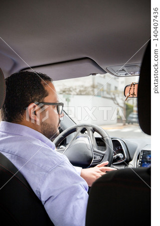 A man in a white shirt is driving a car 140407436