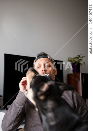 A man is brushing his teeth while a dog looks on A man is brushing his teeth while a dog looks on 140407438