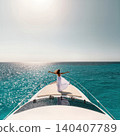 Young woman in white dress standing on yacht bow over turquoise sea 140407789
