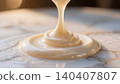 Thick white condensed milk pouring smoothly onto marble surface in warm light 140407807