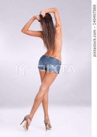 Fashion, shirtless and jeans shorts with woman in studio on gray background for feminine style from back. Model, denim and sexy with body of person in heels or trendy clothes outfit for sensuality Fashion, shirtless and jeans shorts with woman in studio on gray background for feminine style from back. Model, denim and sexy with body of person in heels or trendy clothes outfit for sensuality 140407866