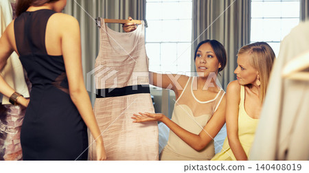 Happy women, trying and dresses in hotel for fashion, support and choice of elegant gown for engagement. Ladies night, bedroom and planning with style clothes as friends and excited together to party Happy women, trying and dresses in hotel for fashion, support and choice of elegant gown for engagement. Ladies night, bedroom and planning with style clothes as friends and excited together to party 140408019