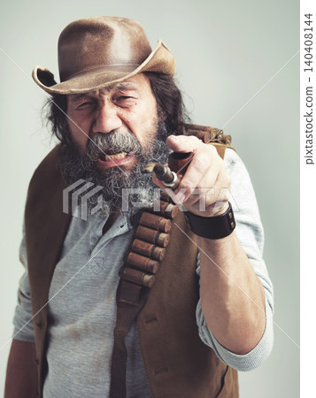 Old cowboy, point and angry face at studio, costume and pipe for western portrait looking scruffy. Senior guy, upset hat and dirty male for texas, grey background and annoyed for accuse gesture Old cowboy, point and angry face at studio, costume and pipe for western portrait looking scruffy. Senior guy, upset hat and dirty male for texas, grey background and annoyed for accuse gesture 140408144