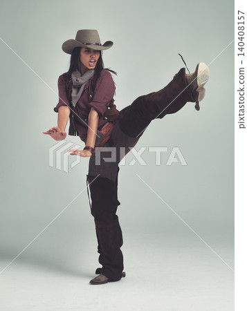 Western, woman and cowboy in studio with fashion, leg up and gesture to fight on grey background. Female person, vintage and outlaw with boots for wild west, costume and character with retro hat 140408157