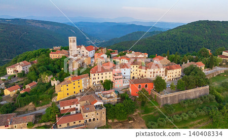 Drone captures medieval hilltop town of Oprtalj located in inland Istria. Historic stone houses, cypress trees, and ancient bell tower stand above picturesque countryside vineyards and fields. Drone captures medieval hilltop town of Oprtalj located in inland Istria. Historic stone houses, cypress trees, and ancient bell tower stand above picturesque countryside vineyards and fields. 140408334