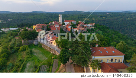 Drone captures medieval hilltop town of Oprtalj located in inland Istria. Historic stone houses, cypress trees, and ancient bell tower stand above picturesque countryside vineyards and fields. Drone captures medieval hilltop town of Oprtalj located in inland Istria. Historic stone houses, cypress trees, and ancient bell tower stand above picturesque countryside vineyards and fields. 140408335
