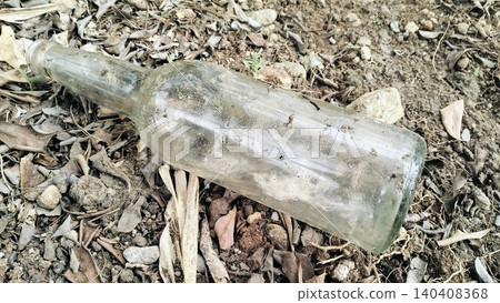 Dirty Empty Glass Bottle Discarded on Dry Ground Dirty Empty Glass Bottle Discarded on Dry Ground 140408368