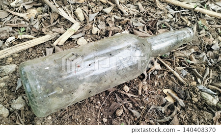 Dirty Empty Glass Bottle Discarded on Dry Ground 140408370