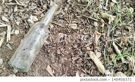 Dirty Empty Glass Bottle Discarded on Dry Ground Dirty Empty Glass Bottle Discarded on Dry Ground 140408371