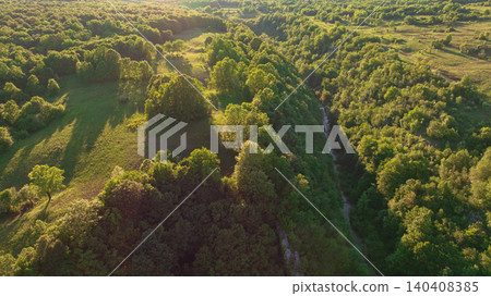 Drone shot displays rural landscape of Dreznik area near Plitvice Lakes. Green agricultural fields, farm lands, and countryside roads spread across traditional Croatian village territory. 140408385