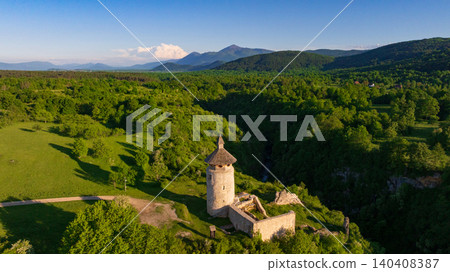 Drone shot displays rural landscape of Dreznik old tower near Plitvice Lakes. Green fields, farm lands, and countryside roads spread across traditional Croatian village territory. Drone shot displays rural landscape of Dreznik old tower near Plitvice Lakes. Green fields, farm lands, and countryside roads spread across traditional Croatian village territory. 140408387