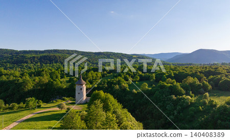 Drone shot displays rural landscape of Dreznik old tower near Plitvice Lakes. Green fields, farm lands, and countryside roads spread across traditional Croatian village territory. Drone shot displays rural landscape of Dreznik old tower near Plitvice Lakes. Green fields, farm lands, and countryside roads spread across traditional Croatian village territory. 140408389