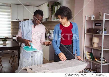 Mother and Daughter Ironing Clothes Together at Home Mother and Daughter Ironing Clothes Together at Home 140408529