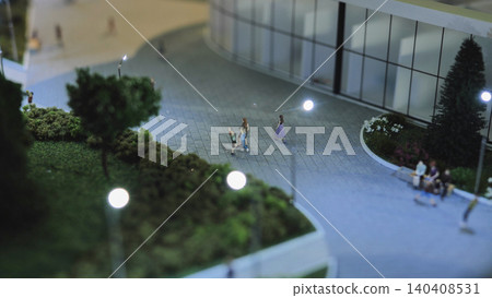 Urban scale model showing architectural design and miniature people on a paved plaza Urban scale model showing architectural design and miniature people on a paved plaza 140408531