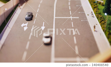 Miniature diorama showing toy cars driving on a road with streetlights and pedestrian Miniature diorama showing toy cars driving on a road with streetlights and pedestrian 140408540