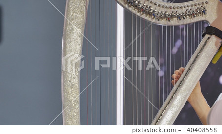 Harpist performing classical music with elegant details, playing strings during a show Harpist performing classical music with elegant details, playing strings during a show 140408558