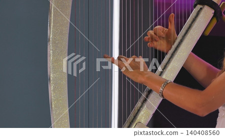 Female musician performing on a harp, creating beautiful music with elegant movements Female musician performing on a harp, creating beautiful music with elegant movements 140408560
