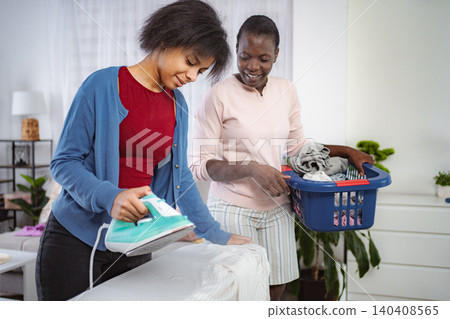 Mother and Daughter Ironing Clothes Together at Home Mother and Daughter Ironing Clothes Together at Home 140408565