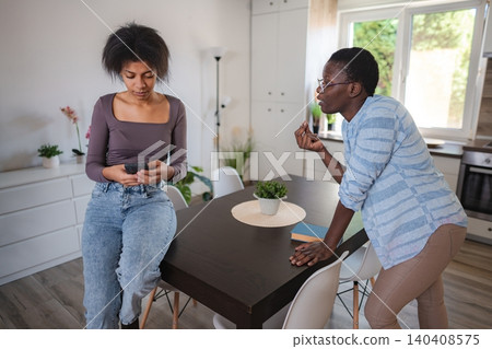 Woman scolding her roommate addicted to her smartphone Woman scolding her roommate addicted to her smartphone 140408575