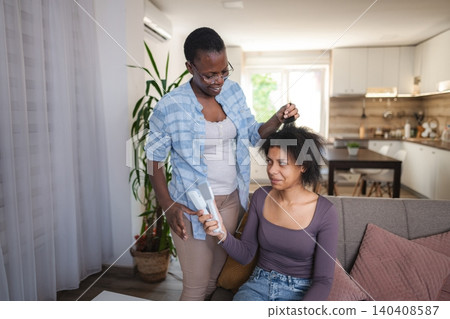 Mother combing and straightening her teenage daughter's hair at home Mother combing and straightening her teenage daughter's hair at home 140408587