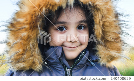 Young child smiling, wearing winter coat with fur hood outdoors, enjoying cold weather Young child smiling, wearing winter coat with fur hood outdoors, enjoying cold weather 140408639