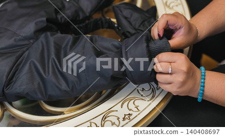 Person adjusting elastic cuff of black winter jacket, preparing clothing Person adjusting elastic cuff of black winter jacket, preparing clothing 140408697