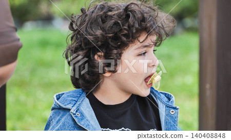 Curly haired child with pacifier outdoors, profile of a kid having a childhood moment 140408848