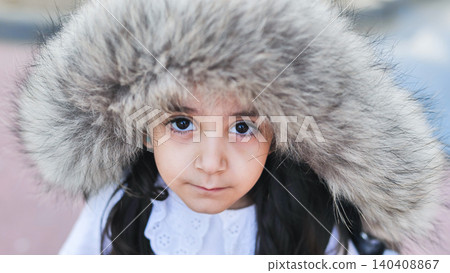 Little girl with big fur hood looking at camera, capturing childhood innocence 140408867