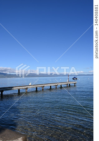 Wooden boat pier dock extending into deep blue alpine lake vertical view. 140408881