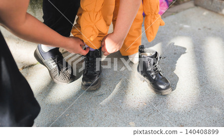 Adult hands helping toddler get dressed, putting on black boots, childhood care Adult hands helping toddler get dressed, putting on black boots, childhood care 140408899
