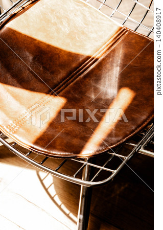 Brown leather chair with chrome wire frame, warm sunlight and glossy texture Brown leather chair with chrome wire frame, warm sunlight and glossy texture 140408917