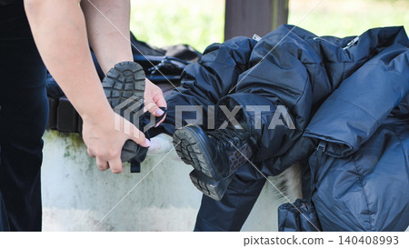 Mother dressing child's foot in black boot, preparing for outdoor activity Mother dressing child's foot in black boot, preparing for outdoor activity 140408993