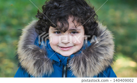 Smiling boy wearing winter jacket with fur hood, enjoying outdoor play in childhood Smiling boy wearing winter jacket with fur hood, enjoying outdoor play in childhood 140409002