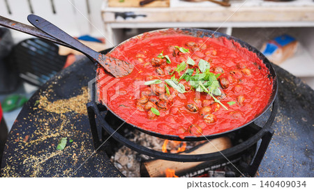 Cooking snails in rich tomato sauce with fresh basil in a large outdoor pan Cooking snails in rich tomato sauce with fresh basil in a large outdoor pan 140409034