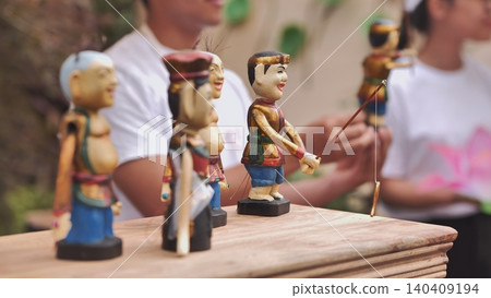 Traditional Vietnamese water puppets, hand-painted wooden figures for a cultural show. A fisherman puppet is in focus with people blurred in the background. Traditional Vietnamese water puppets, hand-painted wooden figures for a cultural show. A fisherman puppet is in focus with people blurred in the background. 140409194
