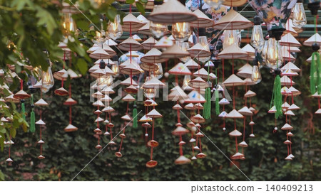 Vietnamese traditional conical hats hanging with light bulbs illuminating a green background 140409213