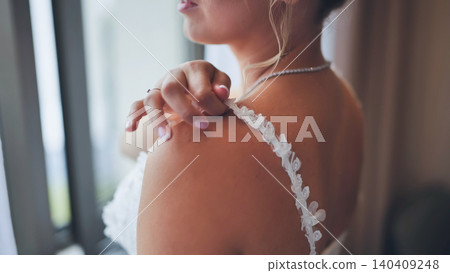 Close up of bride adjusting the delicate lace strap on her shoulder. Close up of bride adjusting the delicate lace strap on her shoulder. 140409248