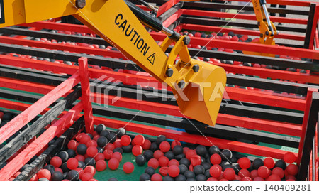 Mechanical arm of excavator toy picking up red and black balls during sports day Mechanical arm of excavator toy picking up red and black balls during sports day 140409281