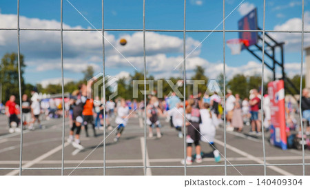 Basketball players competing during a sports day, seen through a wire mesh fence 140409304