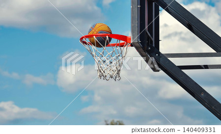 Basketball entering the hoop during a sunny day 140409331