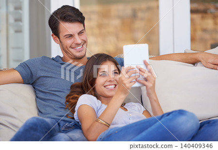 Happy couple, relax and sofa with tablet for entertainment, movie or social media together at home. Man and woman laughing with smile on technology for online streaming, series or show in living room Happy couple, relax and sofa with tablet for entertainment, movie or social media together at home. Man and woman laughing with smile on technology for online streaming, series or show in living room 140409346