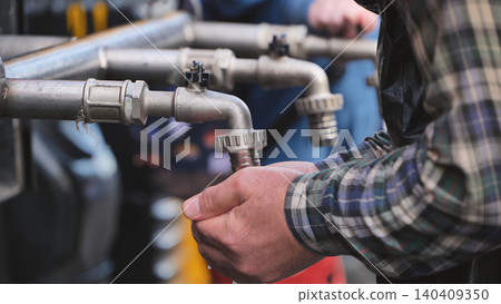 Person collecting fresh water in cupped hands from an outdoor tap for drinking 140409350